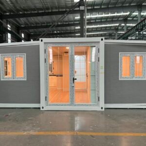 Front view of a gray expandable container house with warm exterior lighting and a cozy modern design