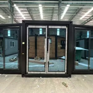 Front view of a gray expandable container house with a full glass facade