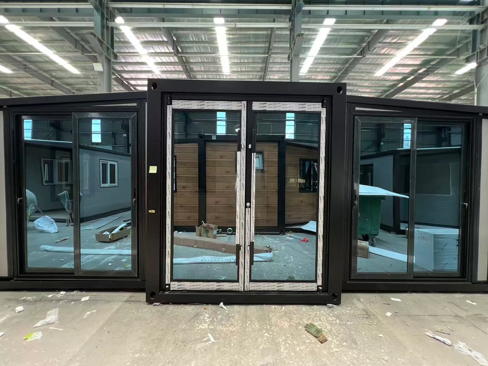 Front view of a gray expandable container house with a full glass facade