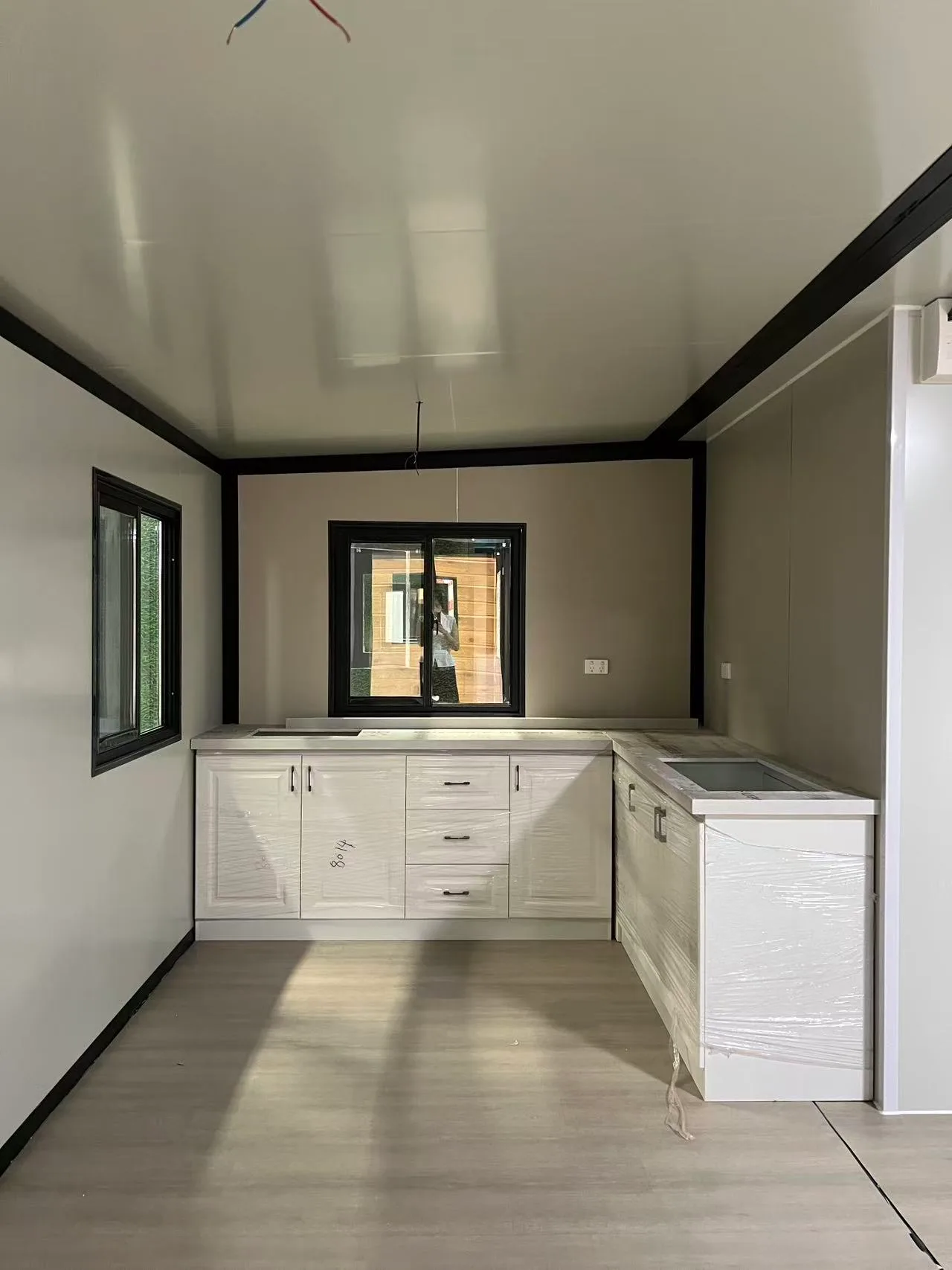 Modern living room with kitchen cabinet inside an expandable modular home with a large glass front wall